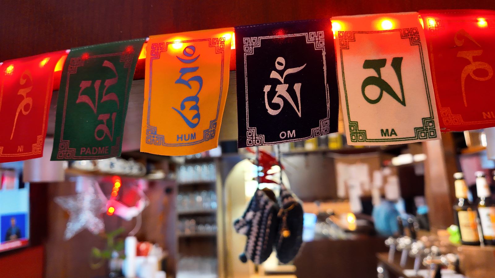 Bunte tibetische Gebetsfahnen mit dem Mantra Om Mani Padme Hum über dem Tresen von Sushi & more in Uelzen